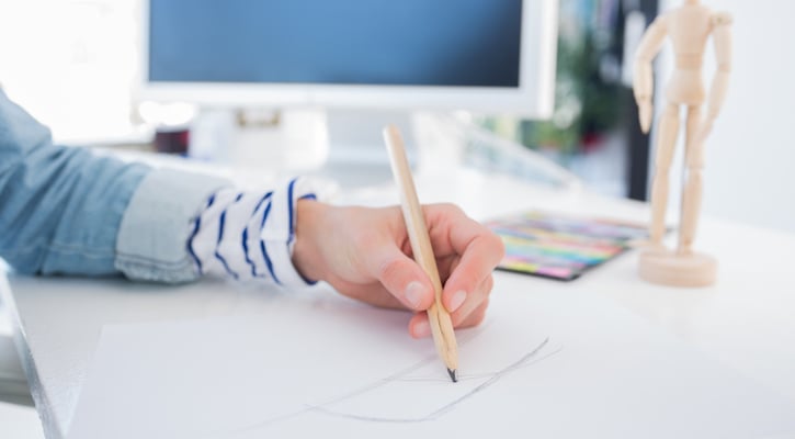 Female hands drawing with pencil on paper on her desk