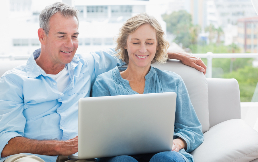 Cheerful couple relaxing on their couch using the laptop at home in the sitting room